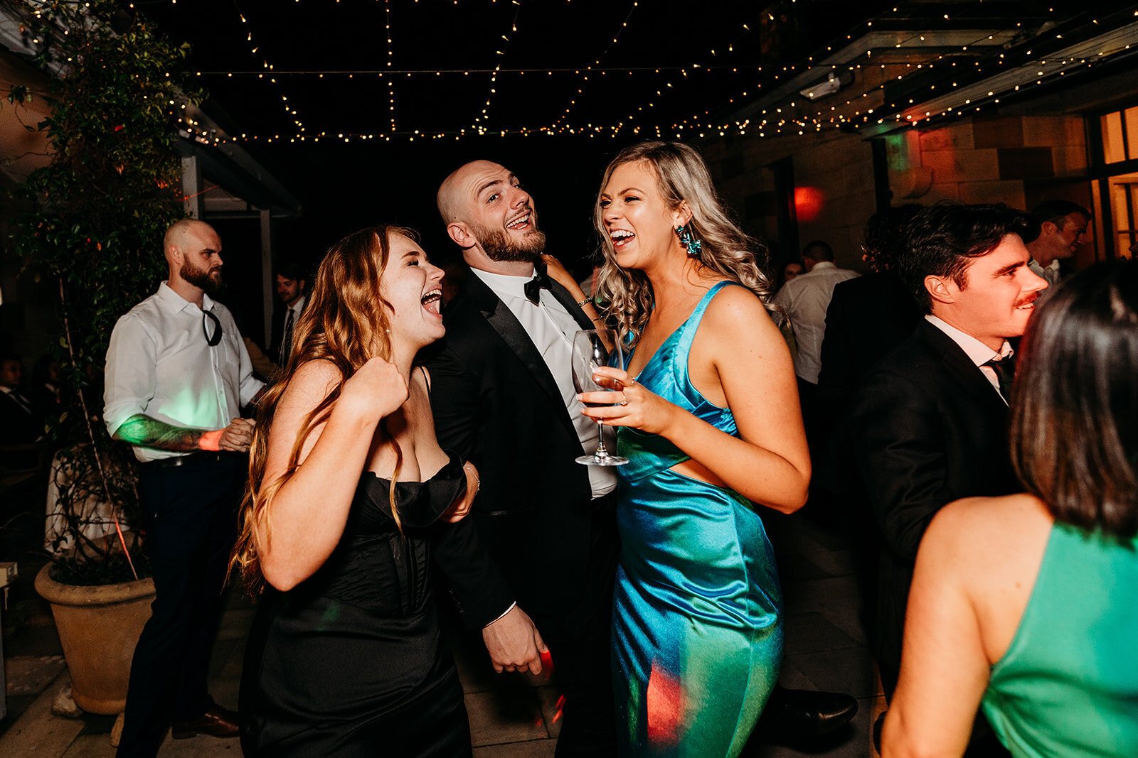 Guests laughing and dancing under festoon lights